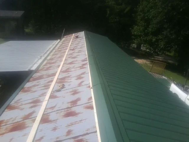 Old rusted panels beside newly installed green metal roofing — Wind Damage Roof Repair by Roofing Brothers in South Butler
