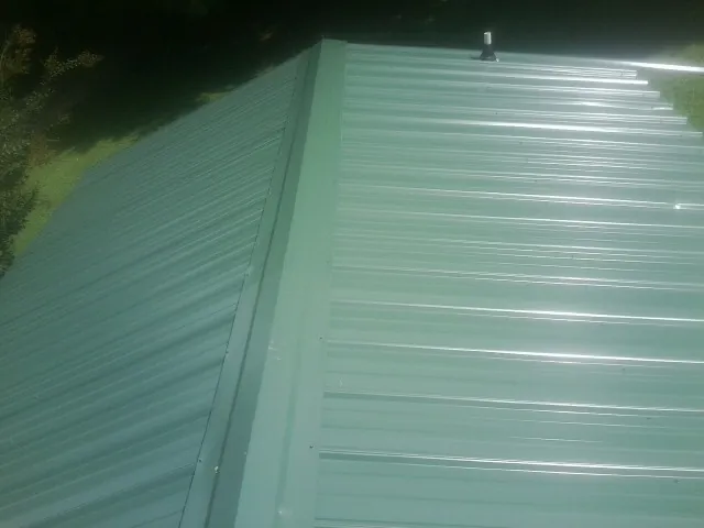 New green metal panels meeting at the ridge of a roof — Flat Roof Repair work by our crew in South Butler