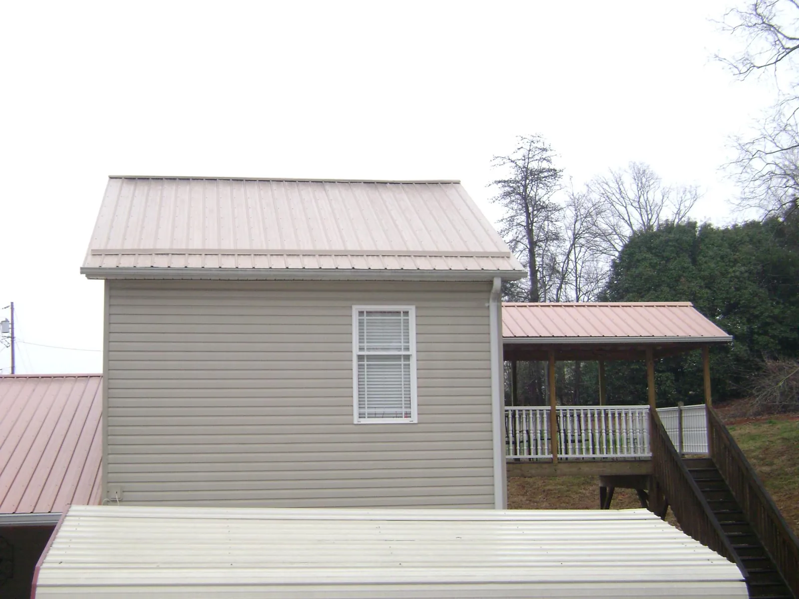 Tan metal roofs on a two story addition and attached porch, from a Roof Replacement job in South Butler