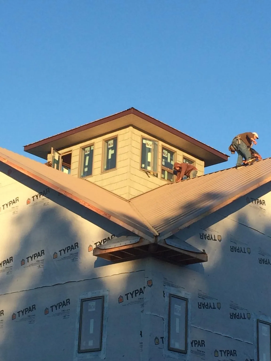 Roofers working around a rooftop cupola on a new metal roof at sunset — Roof Waterproofing in South Butler by Roofing Brothers